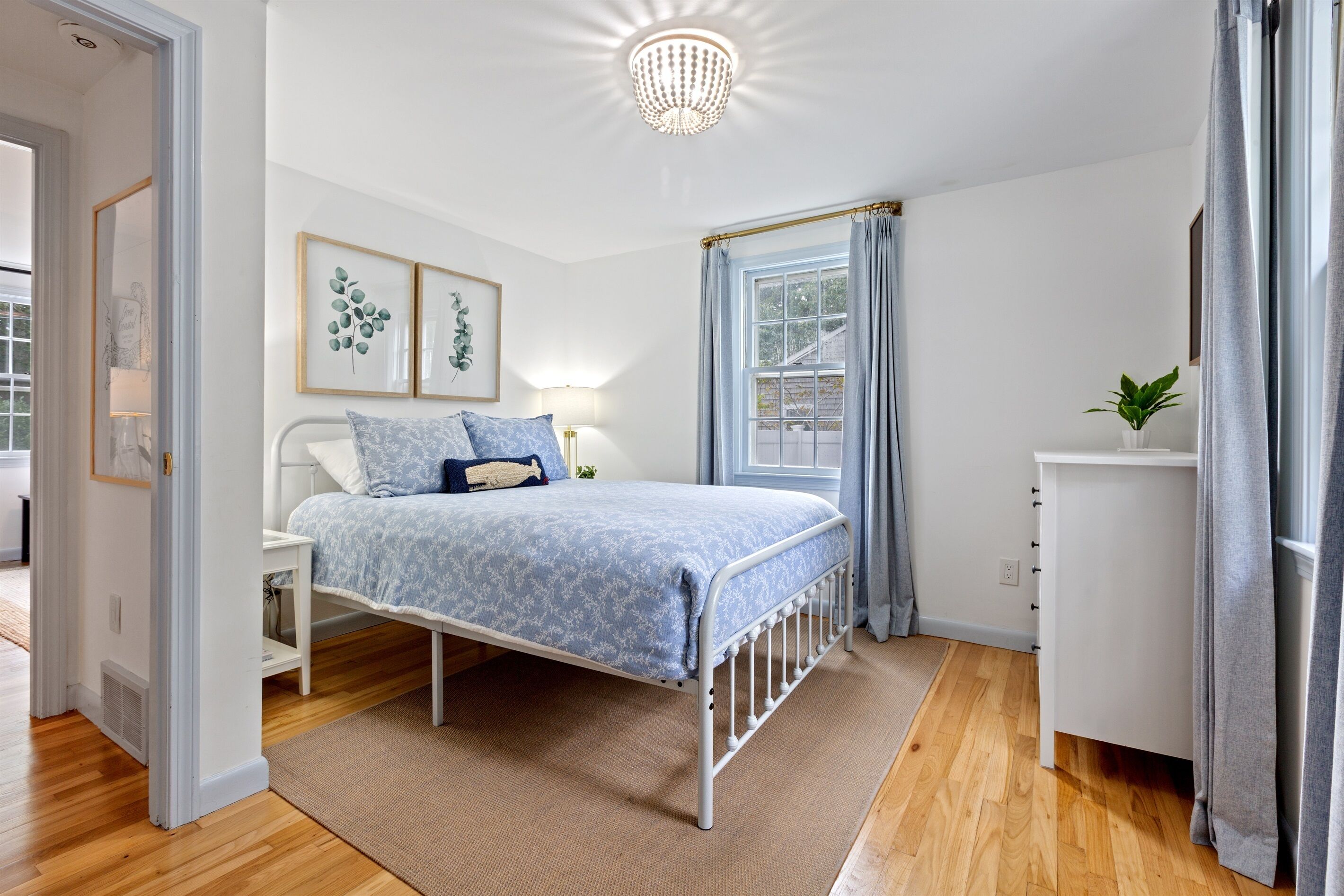 A bedroom with a bed, bedside table, lamp, and a window with curtains.