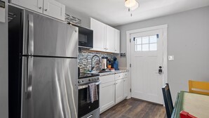 A modern kitchen with stainless steel appliances, white cabinets, and a wooden floor.