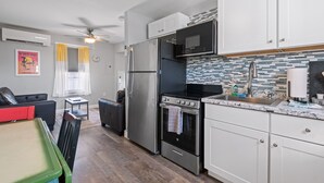 A modern kitchen with stainless steel appliances, white cabinets, and a tiled backsplash. - Steps from Hampton Beach and all entertainment! 2 bedrooms, pet friendly! (Hampton)