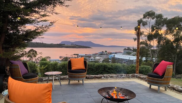 An outdoor seating area with wooden barrel chairs and a central fire pit. - Beautiful Orford with Maria Island Views.
Pet Friendly and Loads of Space (Orford)