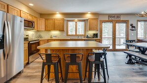 A kitchen with wooden cabinets, a stainless steel refrigerator, a large island with bar stools, and a sign reading 'Grand Lake.' - < 1/2 Mi to Marina: Grand Lake Getaway! (Grand Lake)