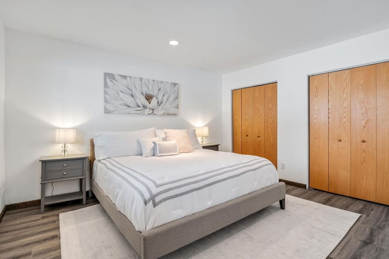 A bedroom with a bed, nightstands, a wall-mounted light, and wooden wardrobes.