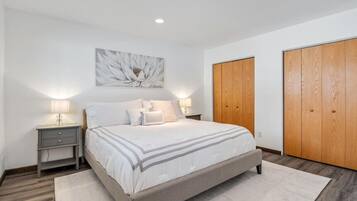 A bedroom with a bed, nightstands, a wall-mounted light, and wooden wardrobes.