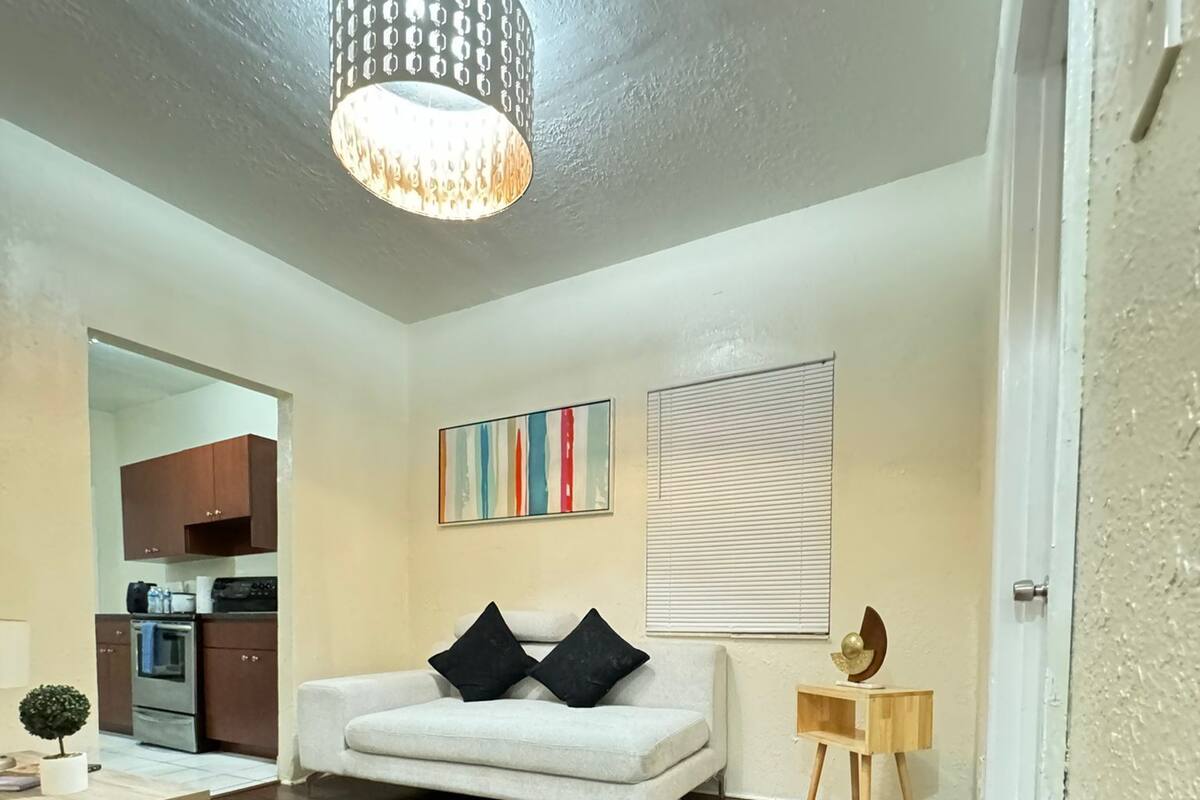 Un salon avec un canapé blanc, une petite table d’appoint en bois, un globe décoratif et une suspension moderne.