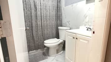 A bathroom with a toilet, a shower curtain, a sink, and a mirror.