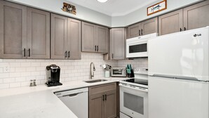 A modern kitchen with brown cabinets, white appliances, and a tiled backsplash. - Walk to everything the inlet has to offer! Amazing bay views! (Ocean City)