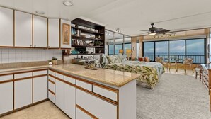 A modern kitchen with white cabinets, a granite countertop, and a built-in bookshelf.