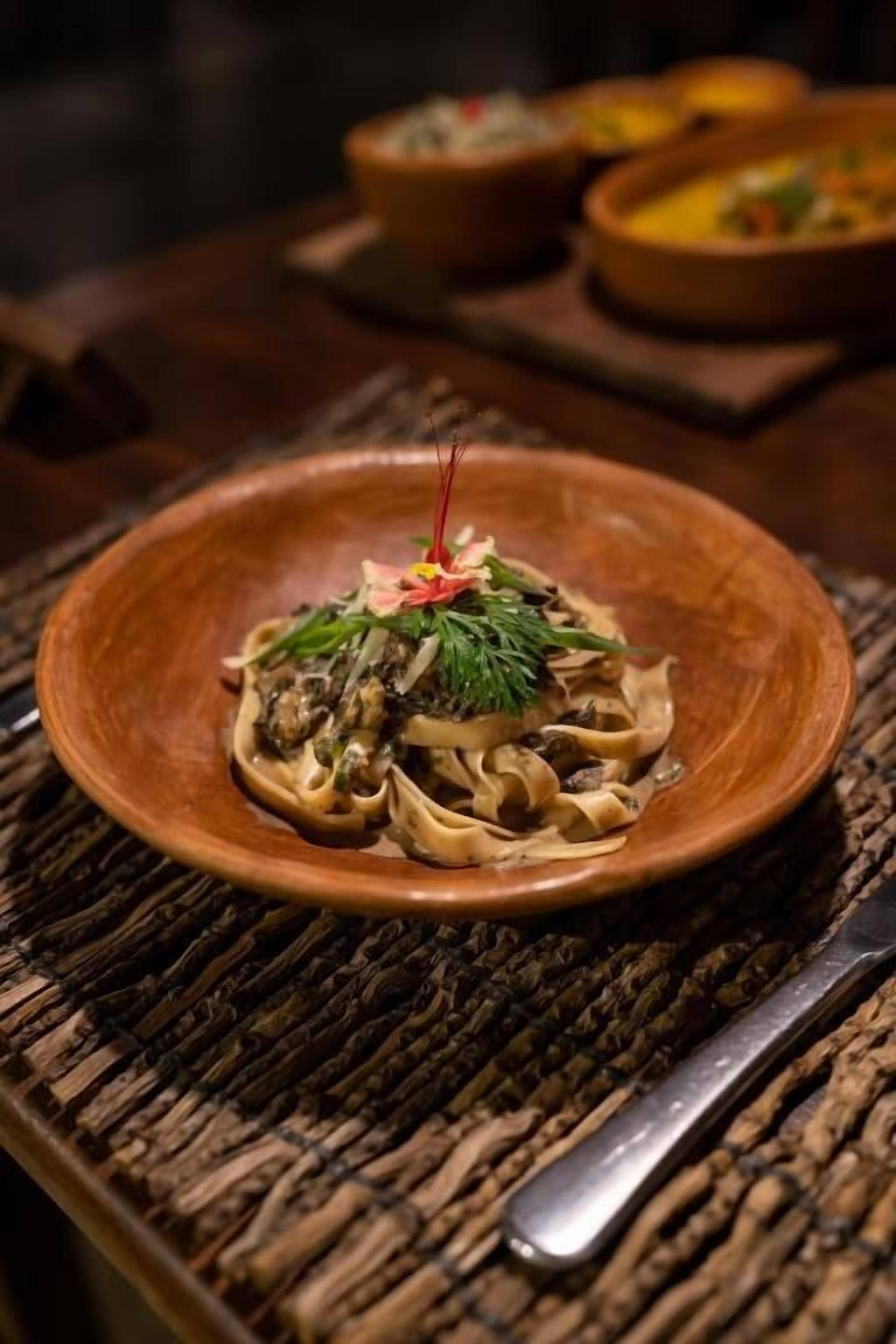 A plate of pasta with a garnish on a woven placemat.