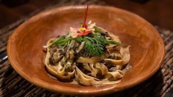 A plate of pasta with a garnish on a woven placemat.