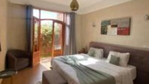 A bedroom with a bed, a desk, and a window.
