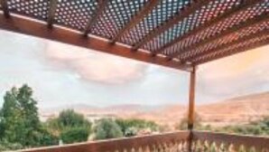 A terrace with a table and chairs, a view of the countryside, and a pergola structure.