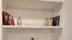 Una estantería con libros, adornos y un cartel que dice 'hogar feliz'.
