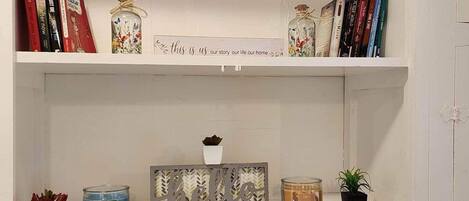 A bookshelf with books, decorative items, and a 'happy home' sign.