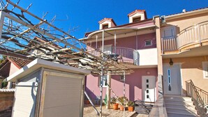 Un edificio residencial con balcón, escaleras y una puerta.