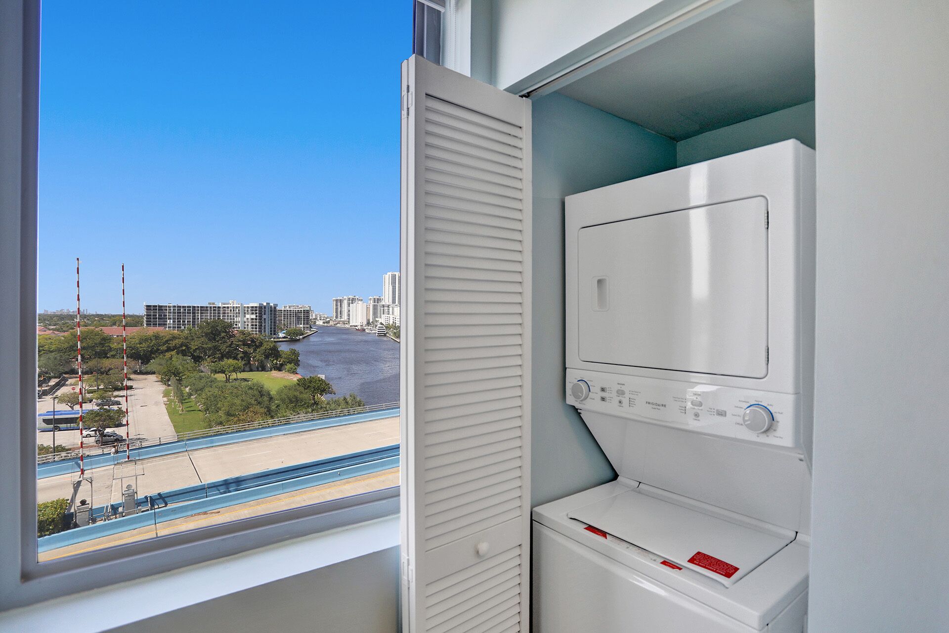 A laundry room with a view of a cityscape through a window.