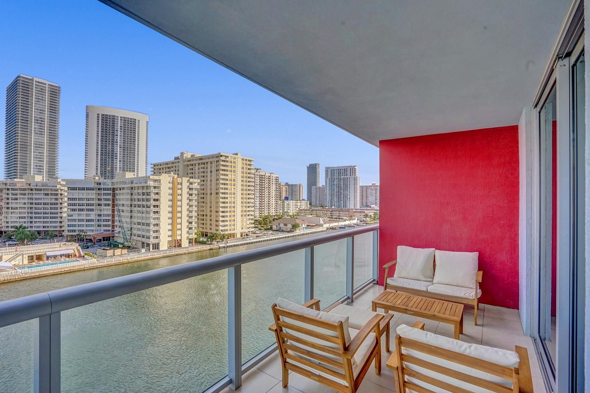 A balcony with a view of a cityscape, including tall buildings and a body of water.