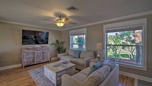 Un salon équipé d’un ventilateur de plafond, d’un téléviseur, d’un canapé, d’une table basse et d’un meuble.