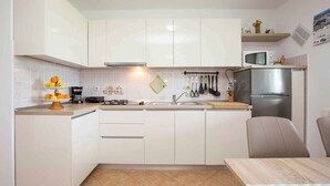 A modern kitchen with white cabinets, a stainless steel refrigerator, and a microwave on the countertop.