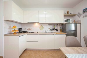 A modern kitchen with white cabinets, a stainless steel refrigerator, and a microwave on the countertop.