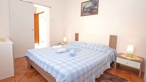A bedroom with a bed, two bedside tables, a nightstand, a door, and a painting on the wall. - Holiday apartment with air conditioning (Rabac)