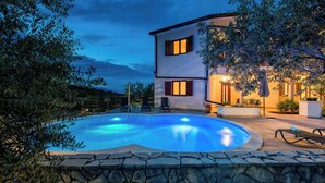 A two-story building with a swimming pool, stone wall, and outdoor seating area. - Holiday apartment with air conditioning (Labin)