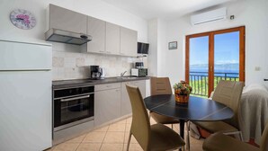 A modern kitchen with a dining area, a large window with a view, and an air conditioning unit. - Holiday apartment with air conditioning (Labin)