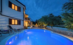 En swimmingpool med solstolar och en byggnad med balkonger.
