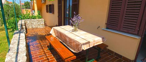 An outdoor patio with a table and benches, surrounded by a brick wall and a stone planter.