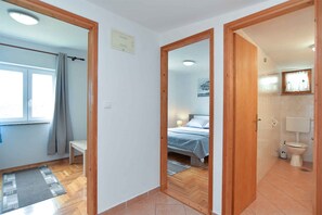 Cozy retreat with a bed, bedside table, and bathroom featuring a toilet and sink.