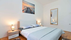 Une chambre à coucher avec un lit, des tables de chevet, une commode, un miroir et un tableau au mur.