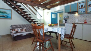 Un comedor con una mesa de madera, sillas y una escalera que conduce a otra habitación.