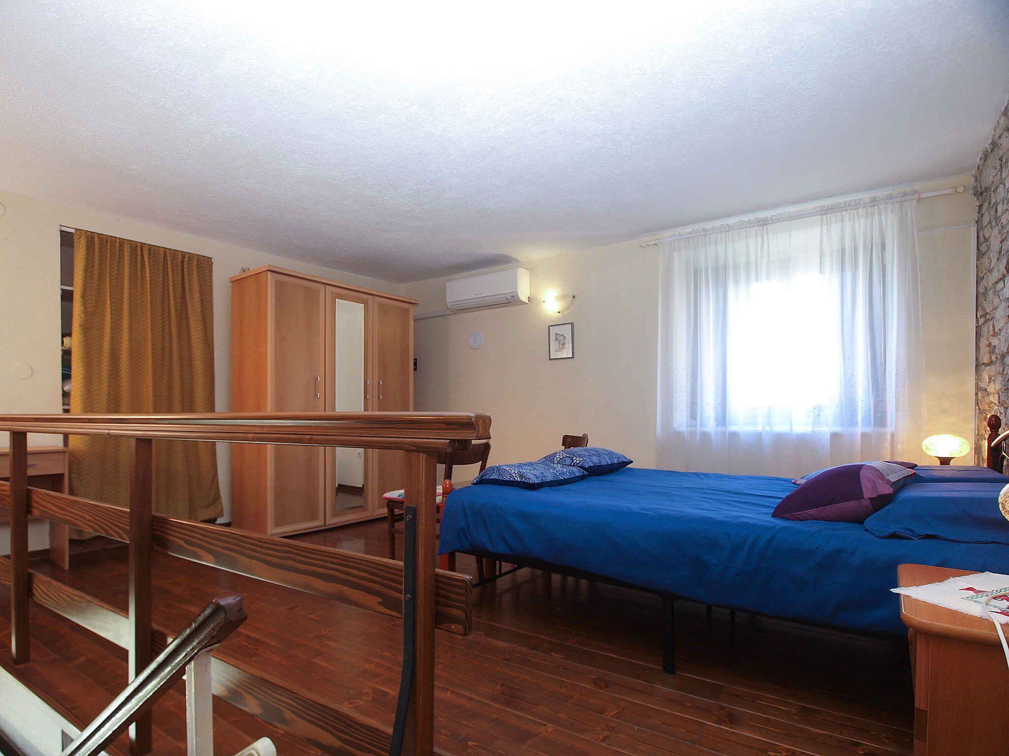 A bedroom with a bed, wooden wardrobe, and a staircase.