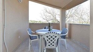 An outdoor patio with a round table and four chairs, a bottle of wine, and glasses on the table.