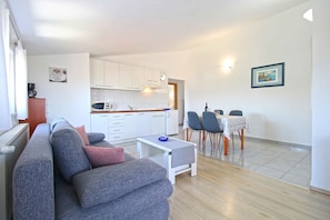 Ein modernes Wohnzimmer mit einem grauen Sofa, einem kleinen weißen Tisch und einem Essbereich mit Tisch und Stühlen.