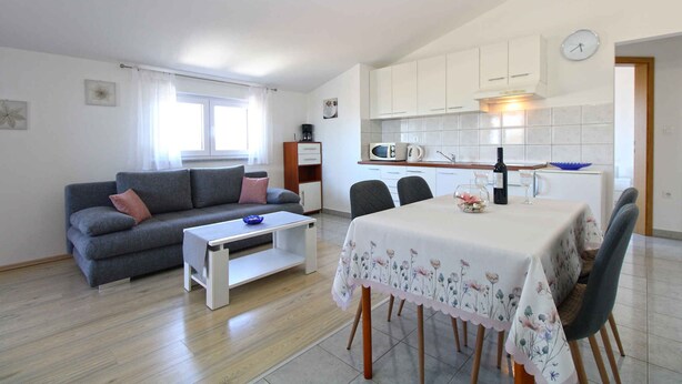 A compact living space with a dining area, kitchenette, and a sofa with a coffee table.