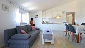A modern living room with a grey sofa, a small white coffee table, and a dining area with a table set for four.