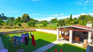 A backyard with a barbecue area, a clothesline, and a small garden. - Holiday apartment with balcony (Valbandon)