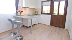 A compact kitchen with a central island, a window with a view, and a wooden door. - Holiday apartment with air conditioning (Fažana)
