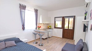 A bedroom with a bed, a desk, and a chair. There is a small kitchenette with a sink and a window. - Holiday apartment with air conditioning (Fažana)
