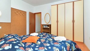 A bedroom with a bed, a wardrobe, a shelf with books, and a corkboard on the wall. - Holiday apartment with air conditioning (Pula)