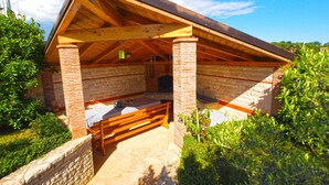 A wooden pavilion with a brick interior, a stone wall, and a checkered tablecloth. - Holiday apartment with air conditioning (Pula)