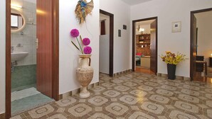 A hallway with patterned flooring, a wooden door, and a vase with purple flowers.