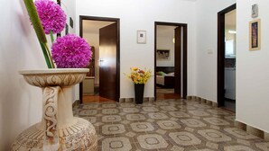 A hallway with patterned flooring, a decorative vase with flowers, and a door leading to a bedroom.
