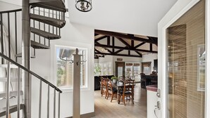 Ein modernes Interieur mit einer Wendeltreppe, einem Holzesstisch und Blick auf einen See.