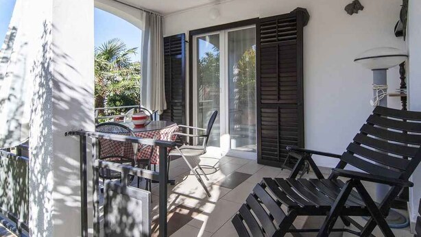 A balcony with a table and chairs, a bench, and a view of greenery outside. - Studio with terrace and air conditioning (Valbandon)