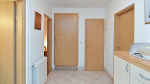A hallway with two wooden doors, a radiator, and a countertop with a sink. - Holiday apartment with terrace and barbecue facilities (Valbandon)