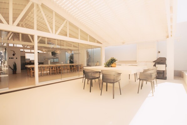 Cocina moderna y espaciosa con una isla grande, paredes de vidrio y un techo alto.