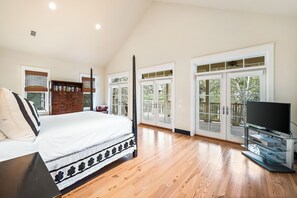 A spacious bedroom with a large bed, a wooden bookshelf, a television, and large windows. - WaterColor Retreat with Beach Club Access, Bikes, and Stylish Design – Serene Luxury Near Seaside! (Santa Rosa Beach)