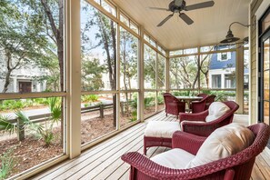 A covered porch with wicker furniture, large windows, and a ceiling fan. - WaterColor Retreat with Beach Club Access, Bikes, and Stylish Design – Serene Luxury Near Seaside! (Santa Rosa Beach)