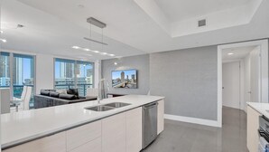 Eine moderne Küche mit einer großen Kochinsel, einem Essbereich mit einer Couch und Blick auf die Stadt durch große Fenster.